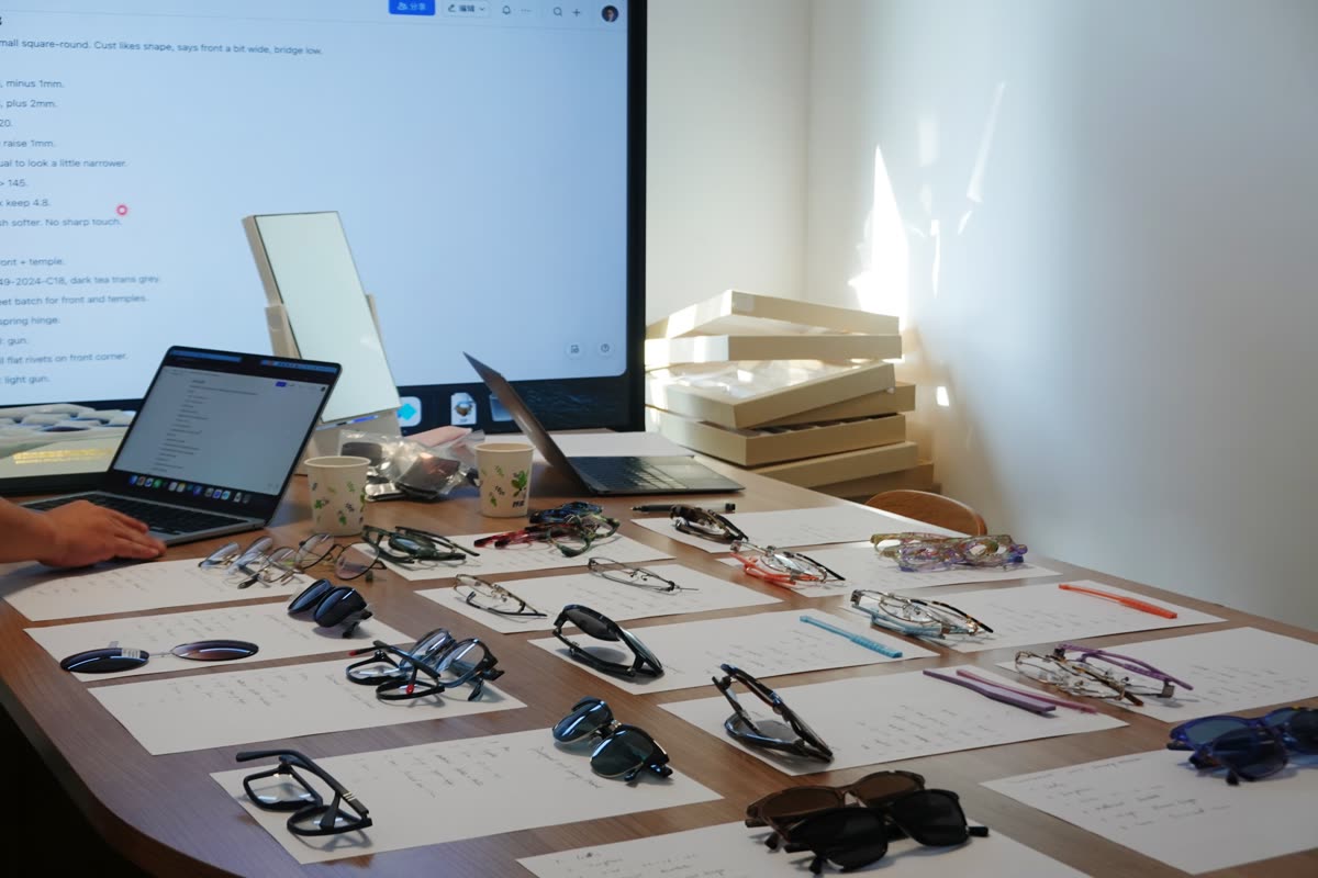 Meeting room with revision notes projected on a screen and frames laid out on handwritten sheets
